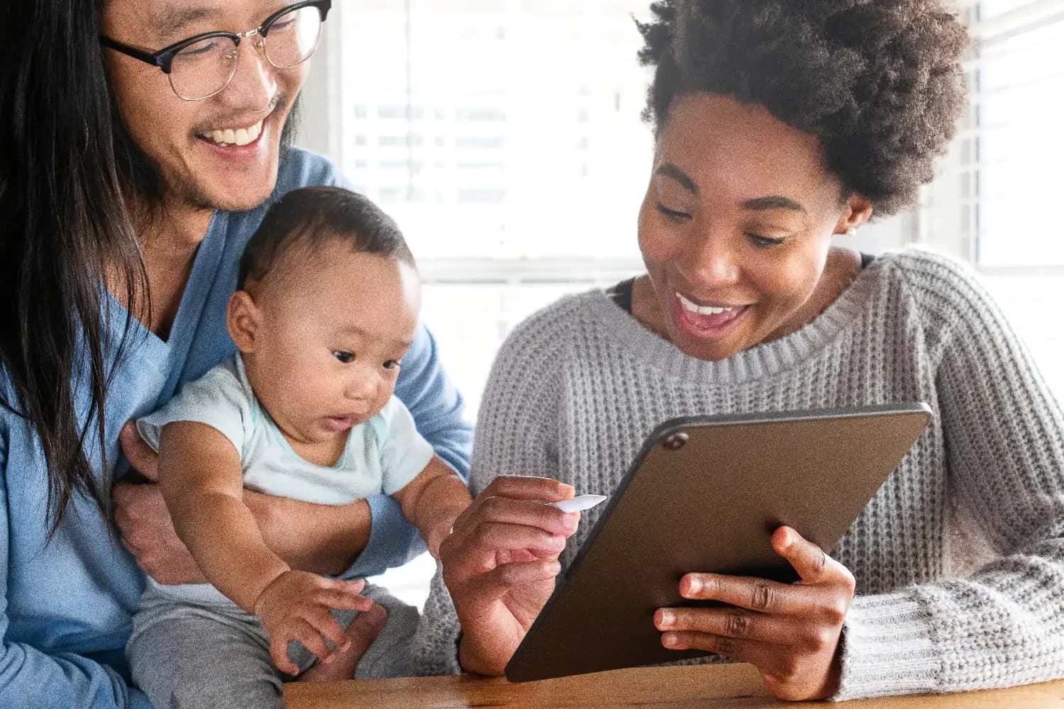 Happy parents with baby, looking at an iPad